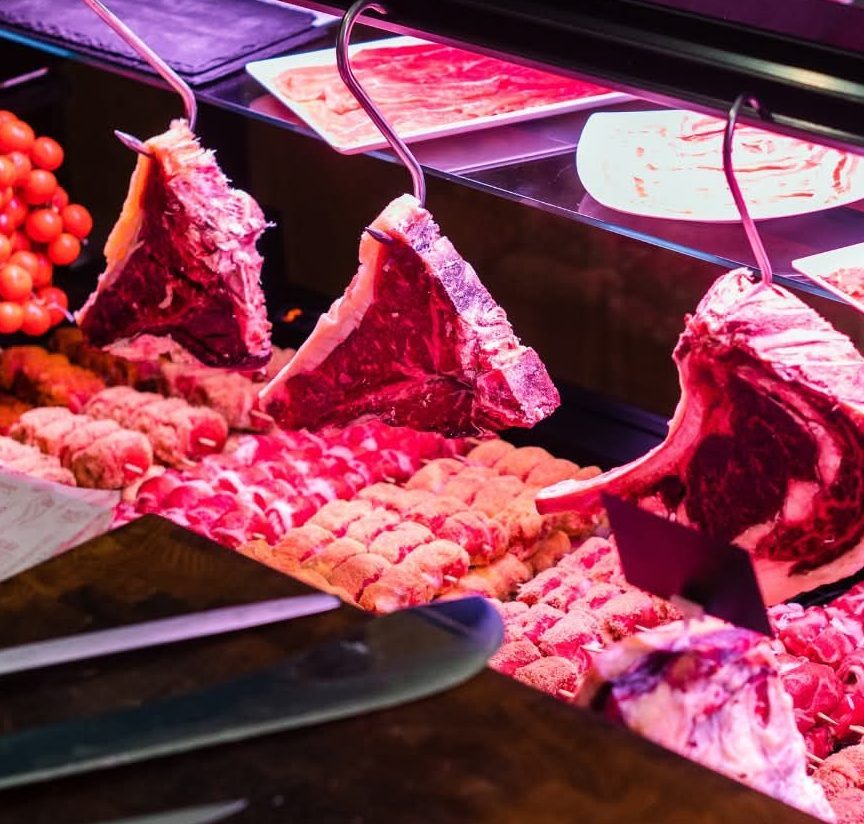 Il banco carni: fiorentine e costate appese, involtini e spiedini in vetrina