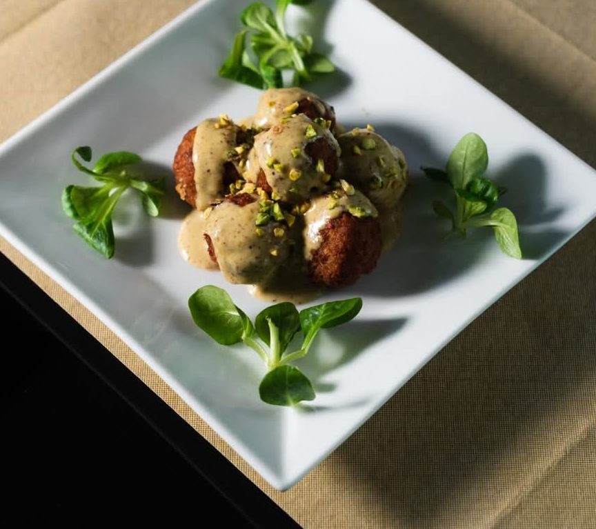 Polpette fritte nappate di crema di pistacchio con granella